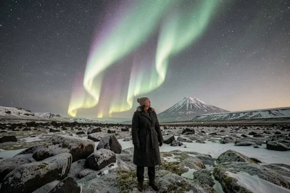 Voyageuse contemplant l'aurore boréale en Islande sur un champ de lave enneigé sous un ciel étoilé